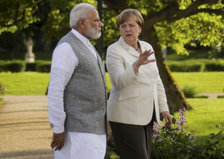 Angela Merkel and Narendra Modi walk through the garden of