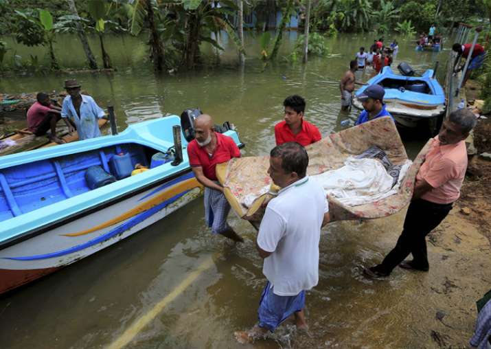 Lankan flood victims carry a woman as she is evacuated from