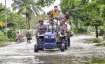Commuters use a tractor to wade through a flooded street,