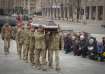 People kneel as the Ukrainian servicemen carry the coffin