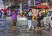 People wade through water logged street after heavy rains
