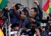 Bolivian President Luis Arce raises a clenched fist surrounded by supporters and media, outside the 