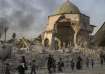 Fleeing Iraqi civilians walk past the heavily damaged al-Nuri mosque as Iraqi forces continue their 