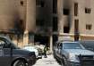 A Kuwaiti police officer is seen in front of a burnt building following a deadly fire, in Mangaf, so