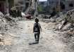 A Palestinian student walks between the rubble after attending a class in a tent set up on the rubbl