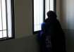 An internally displaced person looks out of a window with a young girl at the Technical Institute of