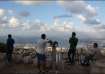 People look over the city of Haifa amid cross-border