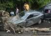 A man sits on a damaged car after a landslide triggered by Tropical Storm Trami in Talisay, Batangas