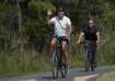 US President Joe Biden waves to a cheering crowd as he rides his bike followed by a Secret Service a