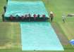 Groundstaff rushes to cover the pitch at St. George's Park in Gqeberha.