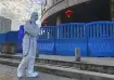 A worker in protectively overalls and carrying disinfecting equipment walks outside the Wuhan Centra