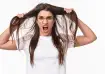Frustrated young woman pulling her hair in stress due to hair fall, wearing white t-shirt