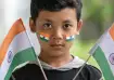 Young Indian boy with tricolour face paint holding two Indian flags during Independence Day