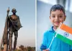 Statue of Mahatma Gandhi with walking stick and a young Indian boy holding the national flag
