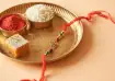 Traditional Rakhi thali with red kumkum, rice grains, a sweet, and a decorative Rakhi