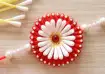 Handmade Rakhi made with red and white cotton buds, decorative pearls, and thread