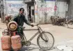 A man carries a domestic LPG cylinder on his bicycle/ Photo