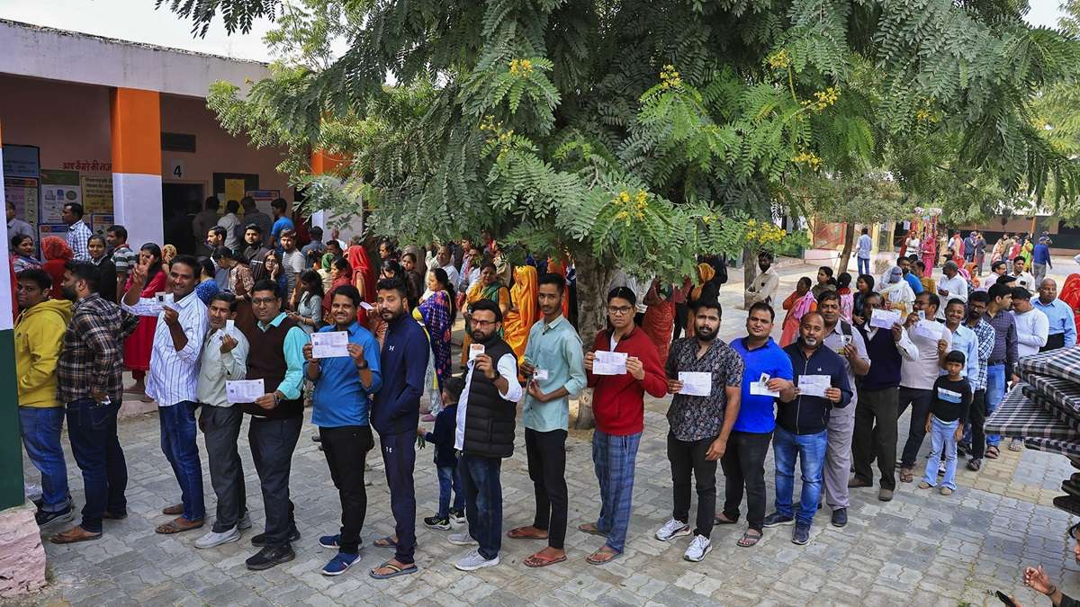 People stand in queue at a polling booth to cast vote
