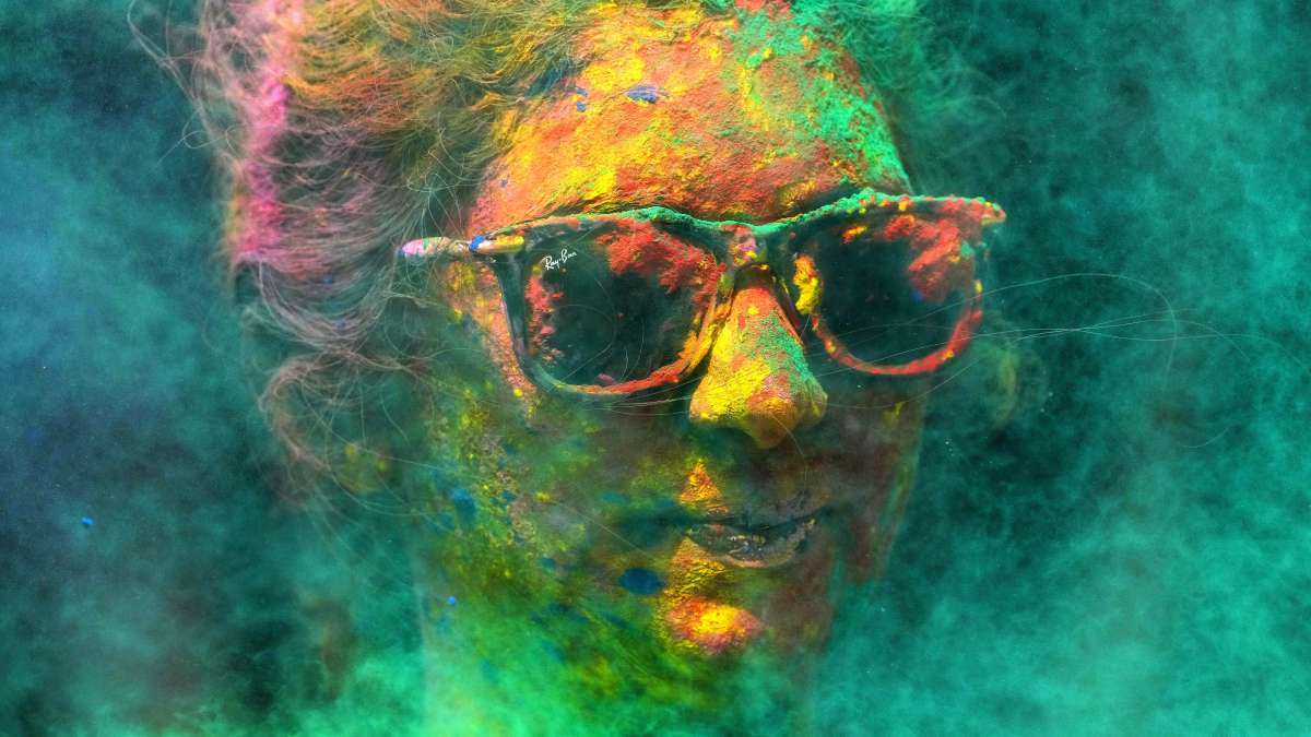 A woman smeared with colours celebrates Holi, the Hindu