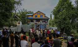 Kashmir villagers and police assemble outside the house of