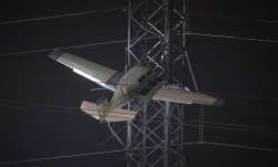 A small plane rests on live power lines after crashing,