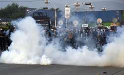 Police officers fire tear gas to disperse the supporters of