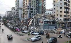 Vehicles drive past damaged buildings in Beirut's southern