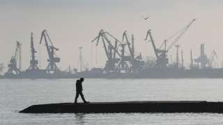 A man walks in front of harbor cranes at the port in
