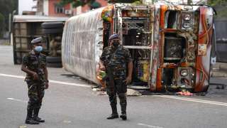 Sri Lankan soldiers stand guard next to burnt buses a day