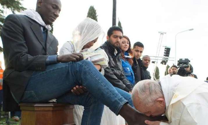 Pope Francis kisses the foot of a man during the