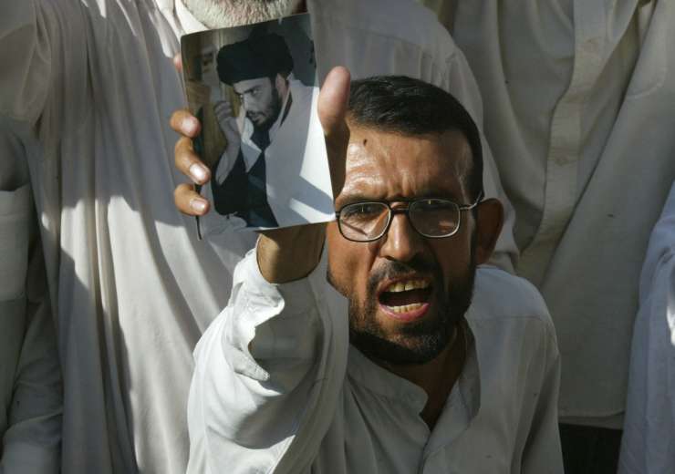 A Shiite Muslim holds up a photo of Shiite Muslim cleric Muqtada al-Sadr at a protest against U.S. troops - India Tv
