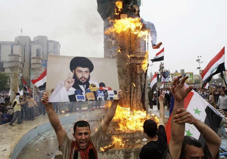  Supporters of anti-U.S. Shiite cleric Muqtada al-Sadr, seen in a poster at left, burn an effigy representing former U.S. President George W. Bush in central Baghdad, Iraq, Thursday, April 9, 2009, for a rally marking the sixth anniversary of the fall of the Iraqi capital to American troops - India Tv