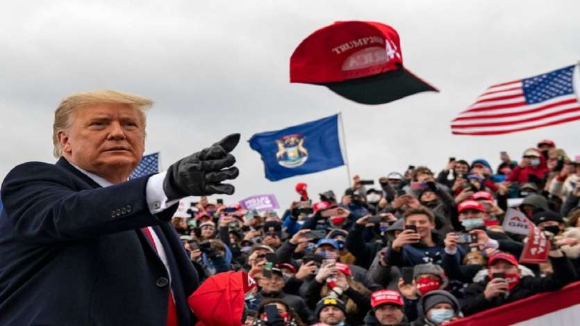 President Donald Trump tosses a cap during a campaign stop in Waterford Township, Michigan.