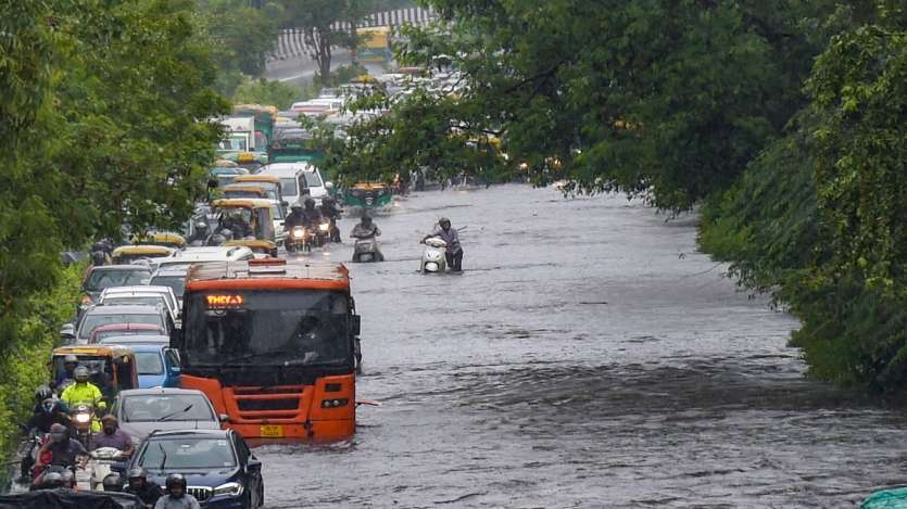 Commuters wade through waterlogged street due to heavy rains, near ITO in New Delhi.