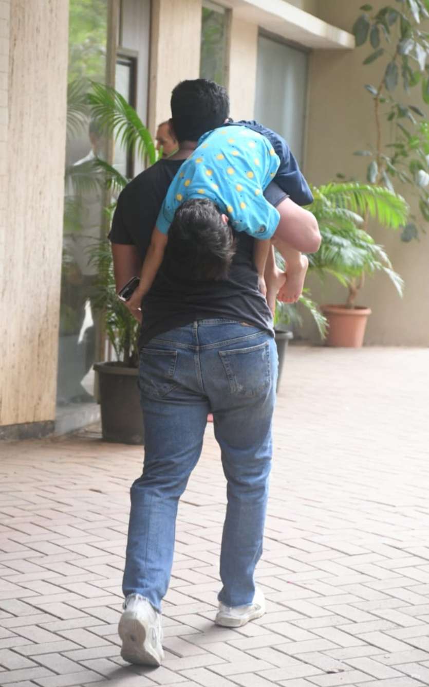 Saif looked dapper as ever in black t-shirt and blue ripped jeans. His white sneakers and cool black shades complemented his overall look. Well, Taimur was hanging on Saif’s shoulder upside down and his attention was on the phone.