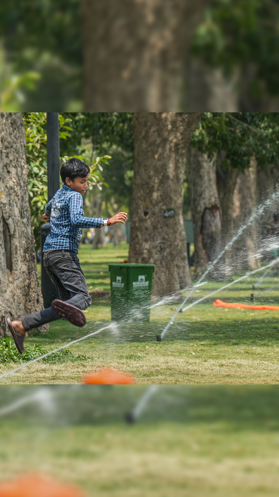 A boy plays near water fountains at an India Gate lawn during hot summer afternoon in New Delhi