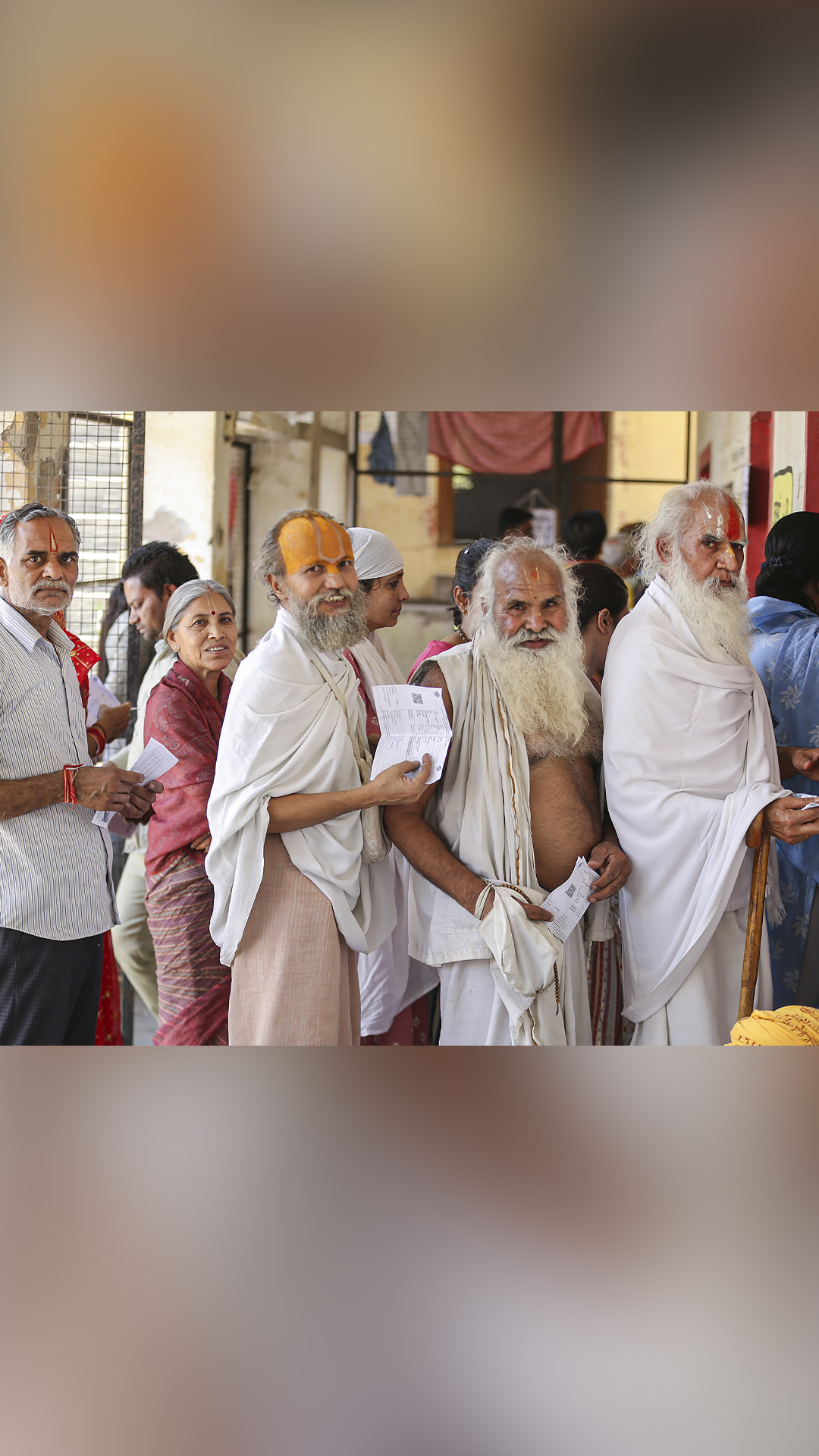 Sadhus wait in a queue to cast their votes for the second phase of Lok Sabha polls, in Mathura

