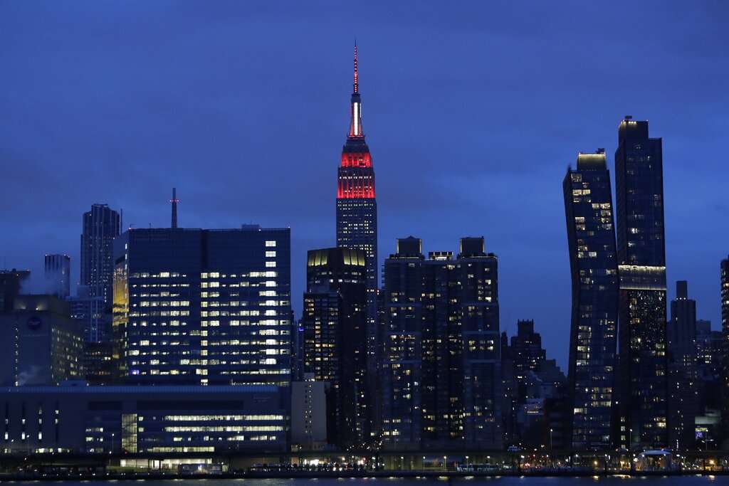 The Empire State building is lit in red and white lights to honor emergency medical workers Tuesday, March 31, 2020, in New York. The new coronavirus causes mild or moderate symptoms for most people, but for some, especially older adults and people with existing health problems, it can cause more severe illness or death.&nbsp;