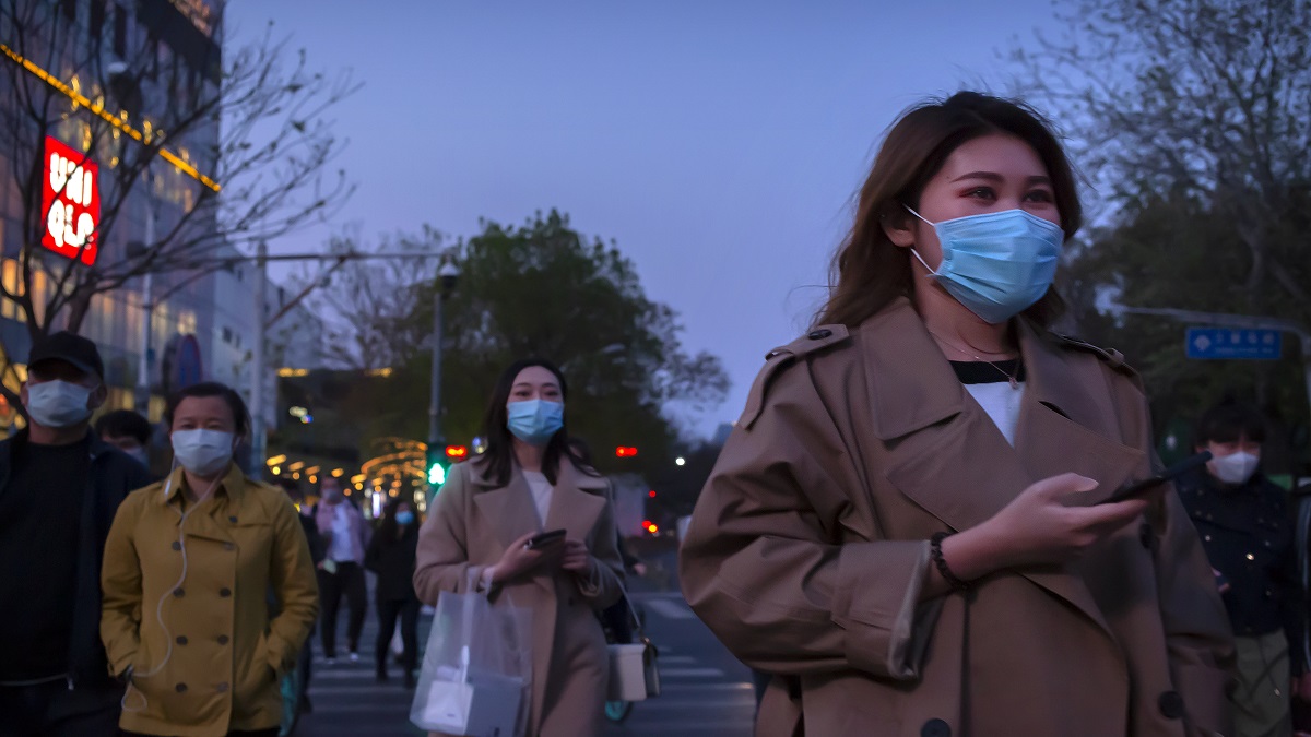 People wear face masks to help curb the spread of the new coronavirus as they cross an intersection in Beijing.