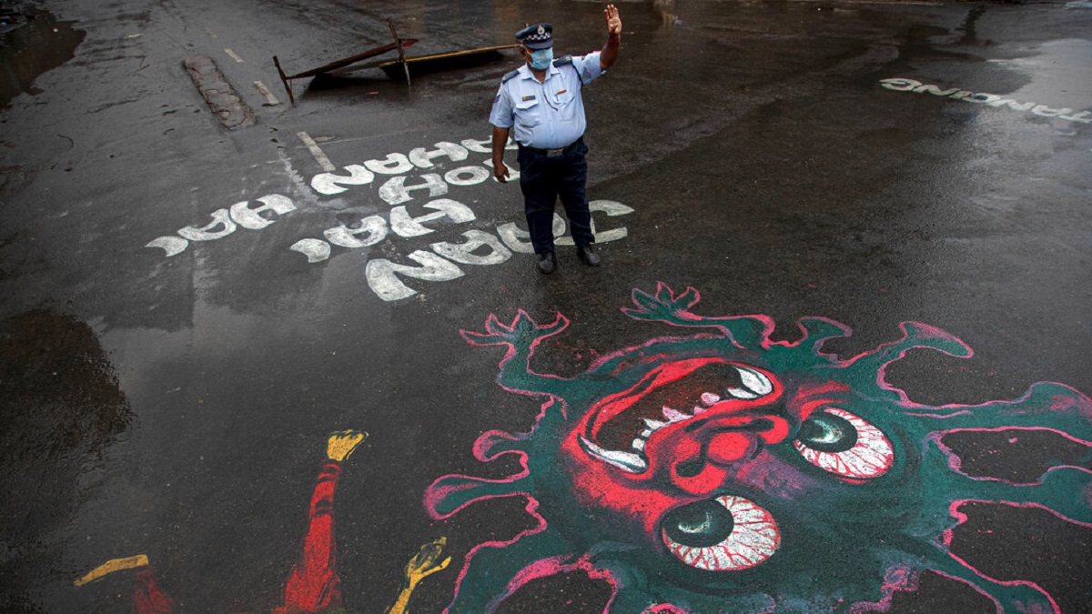 A traffic policeman stands next to an artwork displayed on a road to create awareness about coronavirus during lockdown in Guwahati.