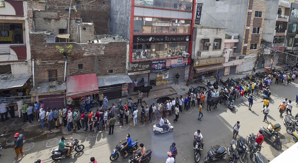 New Delhi: People stand in a long queue outside a wine shop after authorities allowed the sale of liquor with certain restrictions, during the third phase COVID-19 lockdown, at Chander Nagar in East Delhi, Monday, May 4, 2020