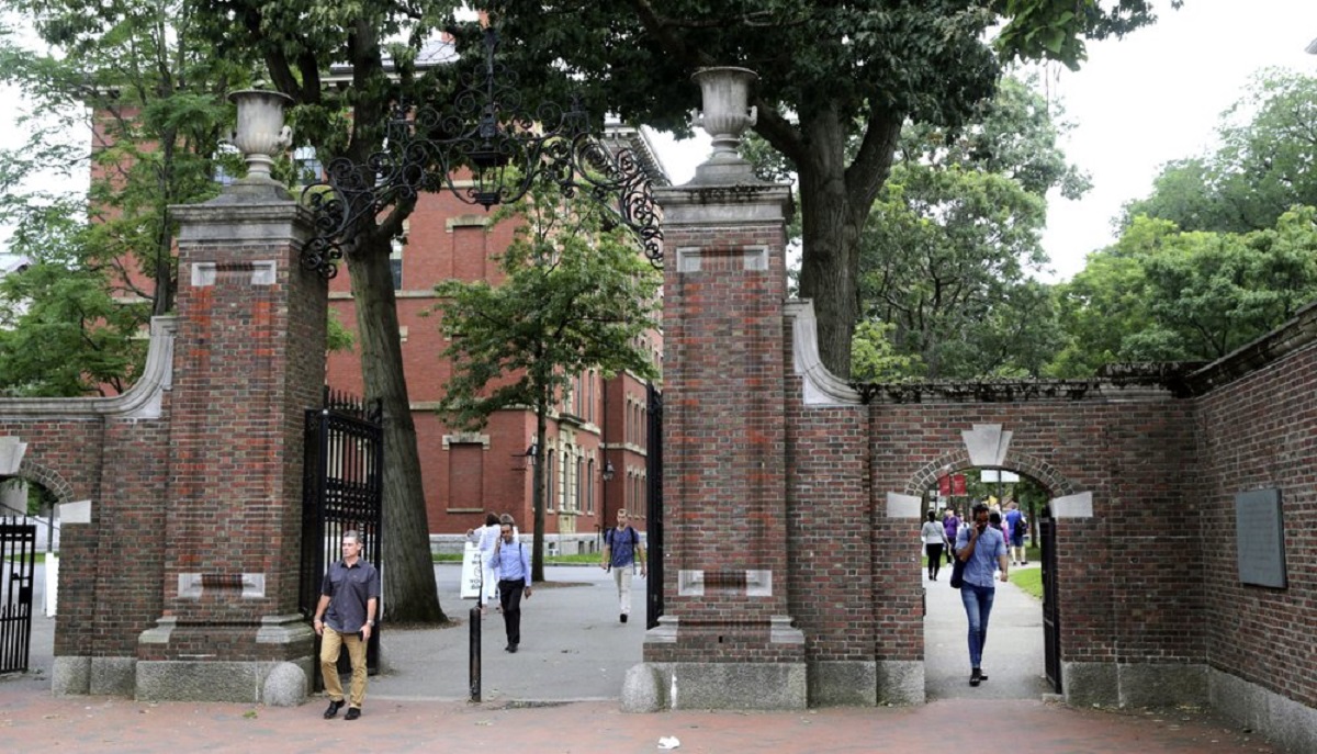 In this Aug. 13, 2019, file photo, pedestrians walk through the gates of Harvard Yard at Harvard University in Cambridge, Mass. Harvard and the Massachusetts Institute of Technology filed a federal lawsuit Wednesday, July 8, 2020, challenging the Trump administration's decision to bar international students from staying in the U.S. if they take classes entirely online this fall. Some institutions, including Harvard, have announced that all instruction will be offered remotely in the fall during the ongoing coronavirus pandemic.