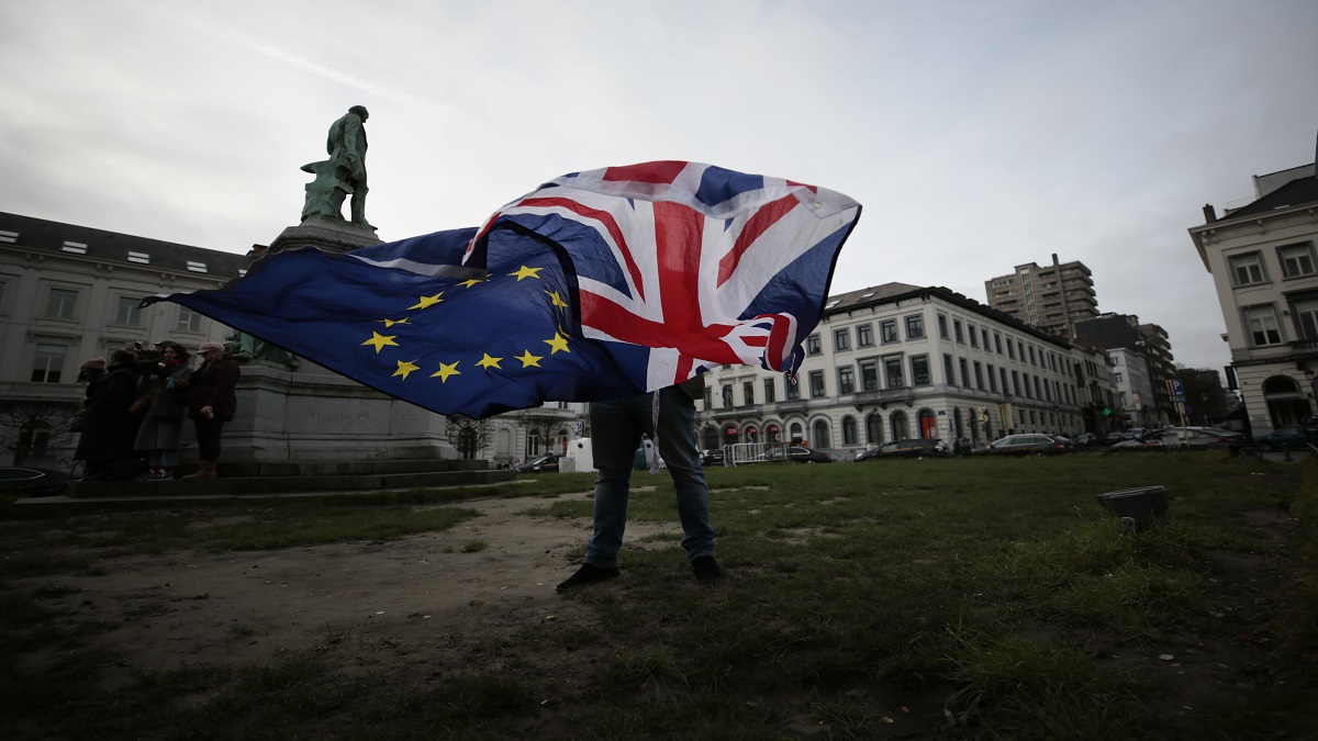 A man unfurls a Union and EU flag outside the European Parliament in Brussels.&nbsp;
