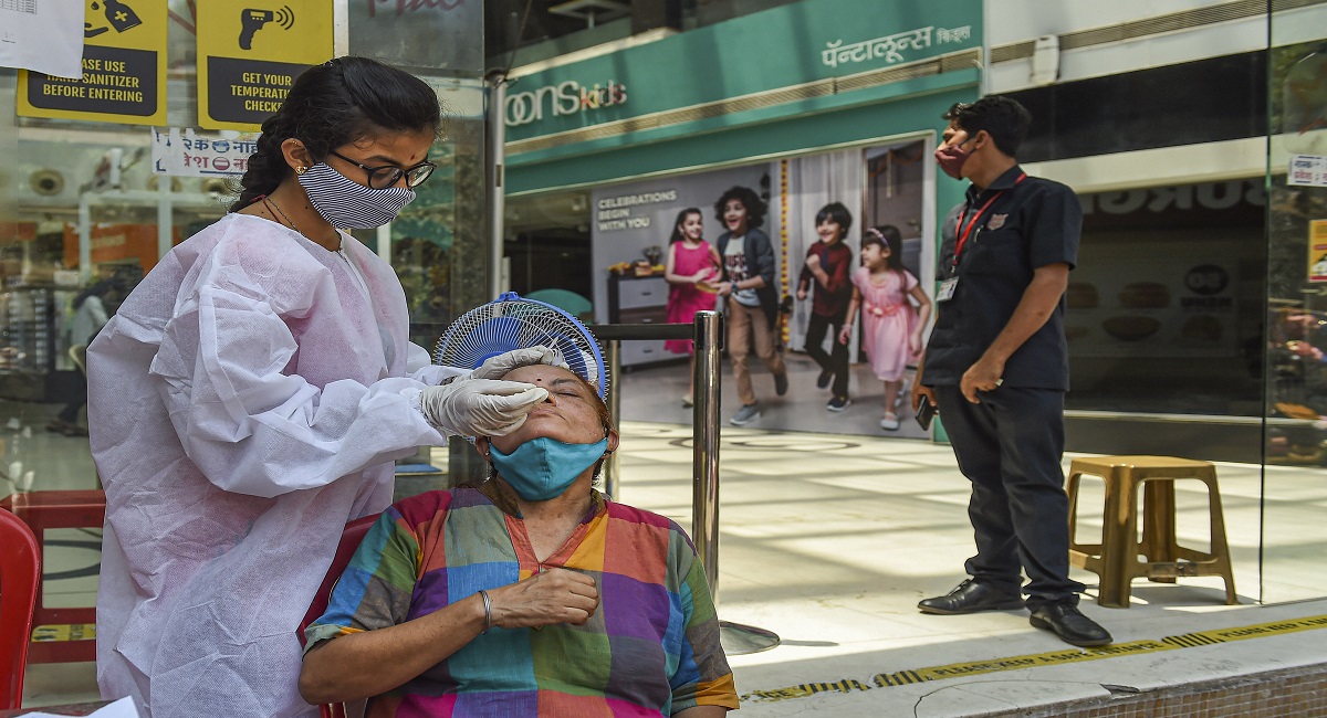 A health worker takes swab sample of a visitor for COVID-19 test at a mall in Mumbai.