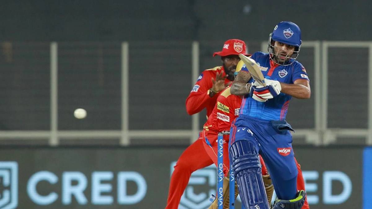 DC opener Shikhar Dhawan plays a shot as PBKS's Chris Gayle (behind) looks on in Ahmedabad on Sunday (May 2, 2021).