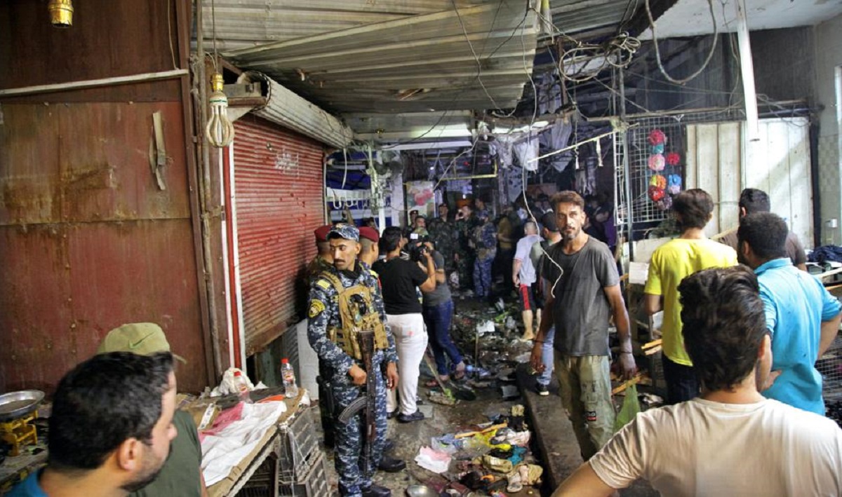 People and security forces gather at the site of a bombing in Wahailat market in Sadr City, Iraq, Monday, July 19, 2021