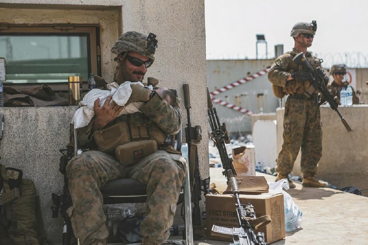 A Marine assigned to the 24th Marine Expeditionary Unit (MEU) calms an infant during an evacuation at Hamid Karzai International Airport, in Kabul, Afghanistan