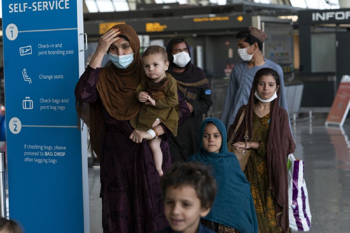 Families evacuated from Kabul, Afghanistan, walk through the terminal before boarding a bus after they arrived at Washington