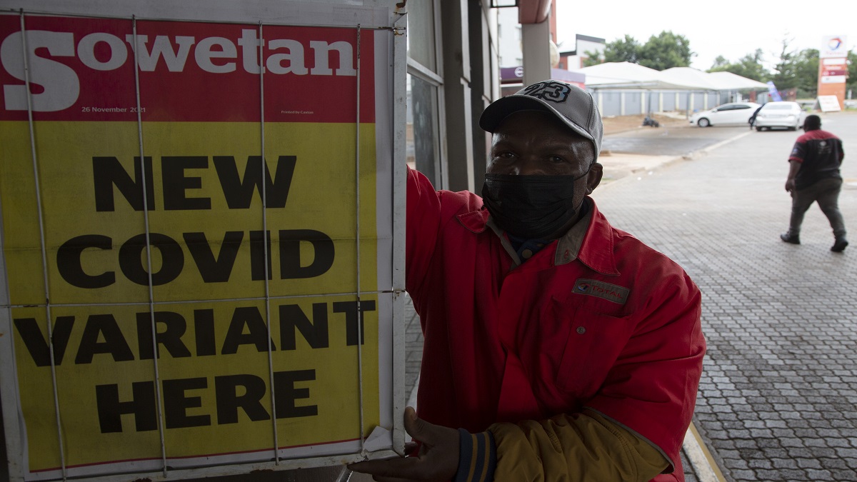 A petrol attendant stands next to a newspaper headline in Pretoria