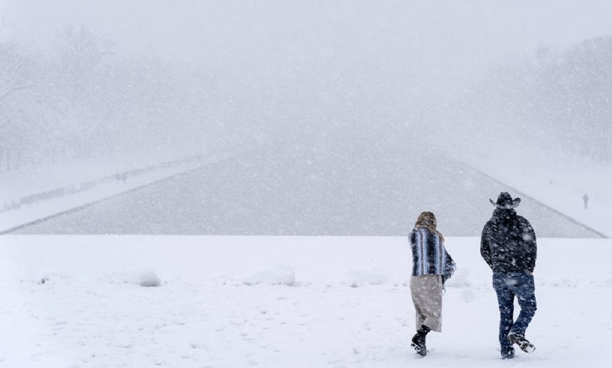 People walk down steps of the Lincoln Memorial with the Lincoln Memorial Reflecting Pool in the background as snow falls
